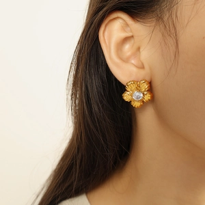 Vintage gold camellia flower earrings with rhinestone center on model ear