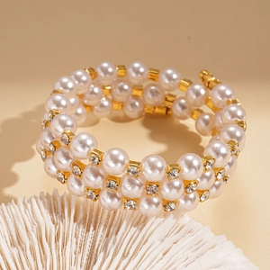 Detail of three-layer pearl bracelet with gold diamond spacers on warm beige base
