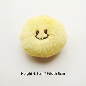 Detail of yellow plush charm with embroidered smile face measuring 4.5cm by 5cm