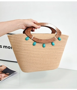 Detail of woven tote bag featuring a wooden D-shaped handle and turquoise stone accent