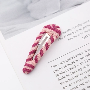 Detail of hand-knitted purple and pink striped hair clip on elegant white paper