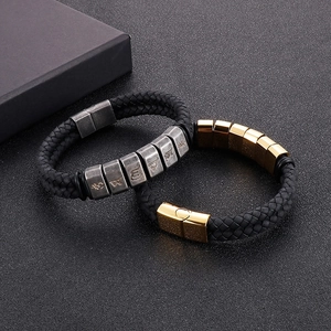 Detail of woven black leather bracelet with silver and gold engraved metal sliders