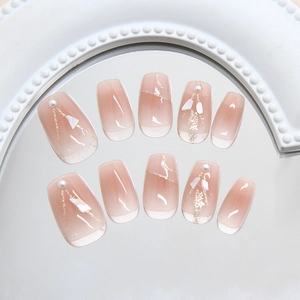 Faux ongles dégradé rose avec French tips blanches, perles et touches de feuilles d'or