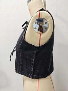 Detailed view of side lacing and metal eyelets on a black denim vest on a mannequin
