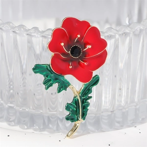 Elegant red enamel flower brooch with green leaves and black gemstone in center