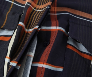 Makroaufnahme von Karohemd-Stoff mit marine-orangen Karos und Nahtdetails