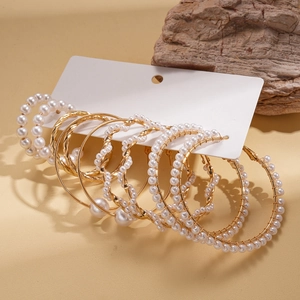 Detail of 10-piece gold pearl hoop earring set on a white card with elegant metallic finish