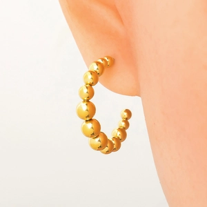 Polished 18k gold plated stainless steel beaded hoop earrings worn by a model