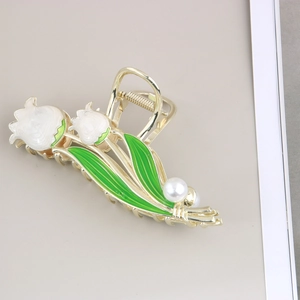 Détail d'une pince à cheveux muguet doré avec fleurs en émail blanc et perle