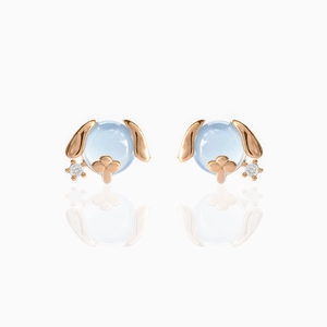 Close-up of light blue gemstone puppy earrings with 18K rose gold and zircon accents