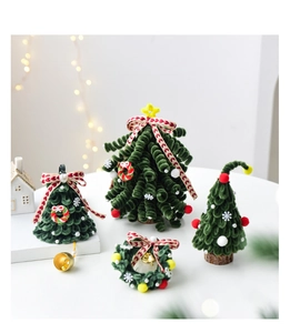 Macro shot of green chenille mini Christmas trees and festive wreaths on white desk