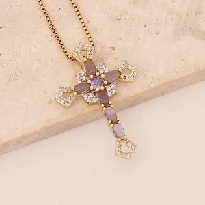 Macro detail of golden cross necklace set with purple oval gemstones and clear zirconias