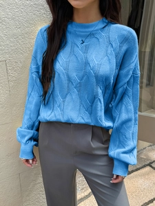 Close-up of blue knit sweater showing detailed leaf-like woven patterns and soft texture