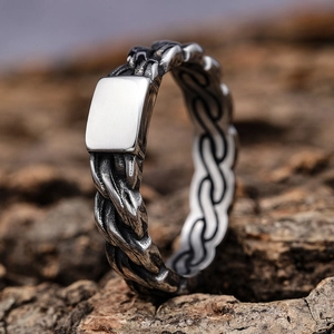 Punk style silver stainless steel ring with woven texture and square flat top on bark