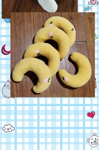 Close-up of yellow crescent plush pet pillow with delicate pink peach embroidery detail