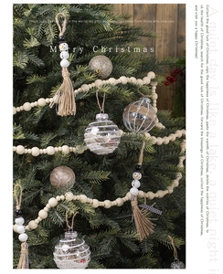Close-up of Christmas wooden snowman ornament and gold glitter balls on green tree branches