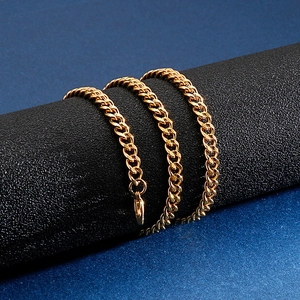 Macro shot of gold curb chain link necklace with lobster clasp on a dark background