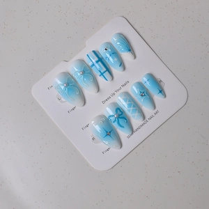 Dettaglio di unghie finte a mandorla 3D con sfumatura blu, perle e fiocchi decorativi