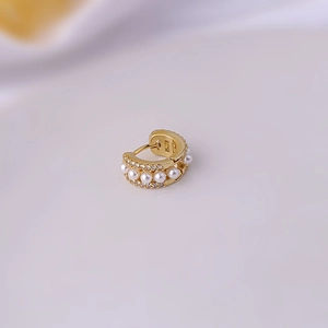 Chic gold hoop earring with white pearls and diamonds on a soft white fabric background