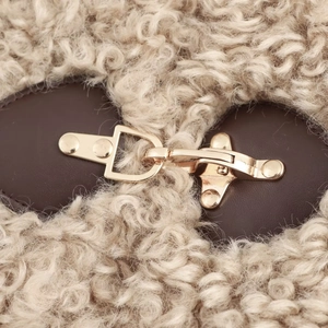 Detail of gold metal buckle on cream fleece fabric with dark brown leather strap trim