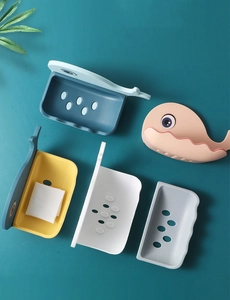 Flat lay of colorful whale-shaped soap dishes with drainage holes on a teal background