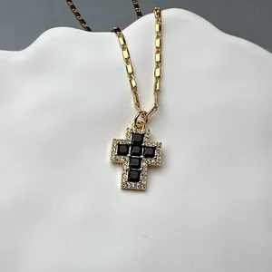 Detailed close-up of gold cross pendant with black onyx and white cubic zirconia