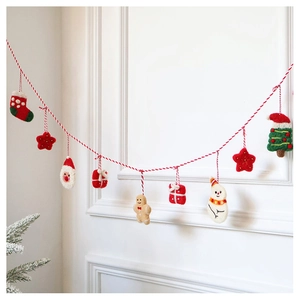 Detail of wool felt Christmas garland featuring gingerbread man and Santa hanging on wall