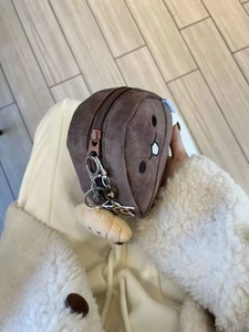 Detail of cute brown plush chestnut pouch with dual zippers and decorative charms