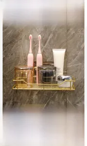 Detail of gold wall-mounted bathroom shelf for toiletries on marble wall background