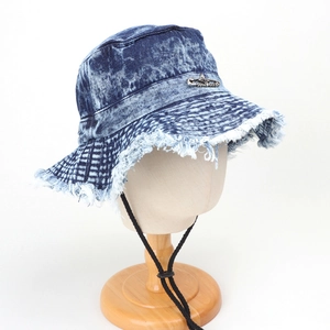 Close-up of frayed edges and metal pin detail on a washed denim bucket hat with cord
