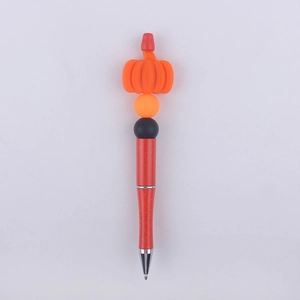 Detail of beaded ballpoint pen featuring orange silicone pumpkin and glittery red barrel