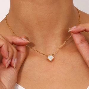 Close-up of heart-shaped opal pendant on a gold necklace worn by a female model