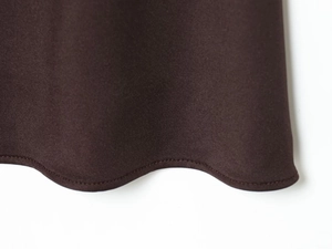 Detail shot of the wavy scalloped hemline and stitching on a brown halter dress