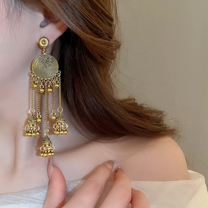 Close-up of vintage gold tassel earrings featuring intricate hollow floral patterns on a model