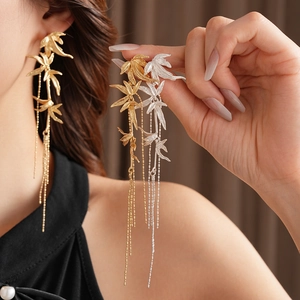 Close-up of bamboo leaf tassel earrings in gold and silver finish on a model