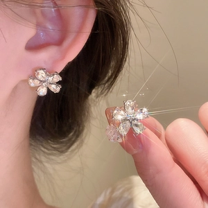 Sparkling diamond-set flower earrings and ring set on model for luxury style