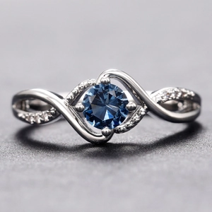 Elegant wavy silver ring featuring a round blue zircon center and micro-pave accents
