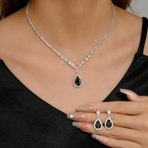 Macro shot of silver necklace and teardrop earrings with black gems on a model