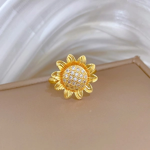 Detail of spinning sunflower ring with gold finish and zircon pave on a jewelry box