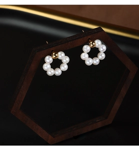 Detail shot of round freshwater pearl hoop earrings hanging on a wood stand