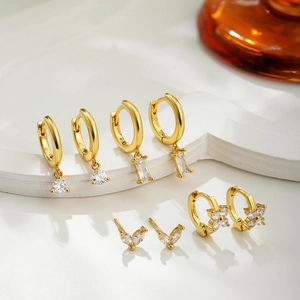Detailed close-up of 18K gold plated earrings set with sparkling zircon on white plaster base