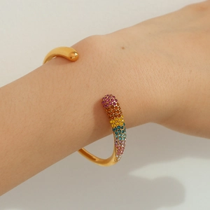 Détail d'un bracelet ouvert doré orné de strass colorés en dégradé scintillant