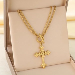 Vue détaillée du pendentif croix dorée et du fermoir à bascule OT sur un collier double