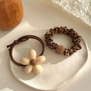 Detail view of floral hair tie and leopard print scrunchie on a decorative white tray