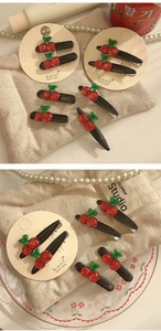 Detail of sweet cherry hair clips with red resin fruit and green leaves on paper card