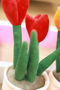 Close-up of plush tulip toy with red and yellow petals and green corduroy leaves