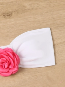 Detail of a large hot pink 3D flower decoration on a white strapless bikini top
