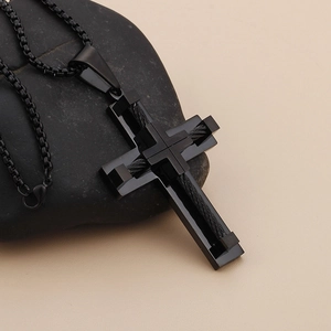 Detail of a black multi-layered cross pendant with woven texture on a dark stone