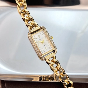 Detailed close-up of a square gold quartz watch with rhinestone bezel and metal chain strap