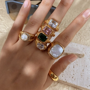 Nahaufnahme von vergoldeten Ringen mit Zirkon und Perlen an der Hand des Models